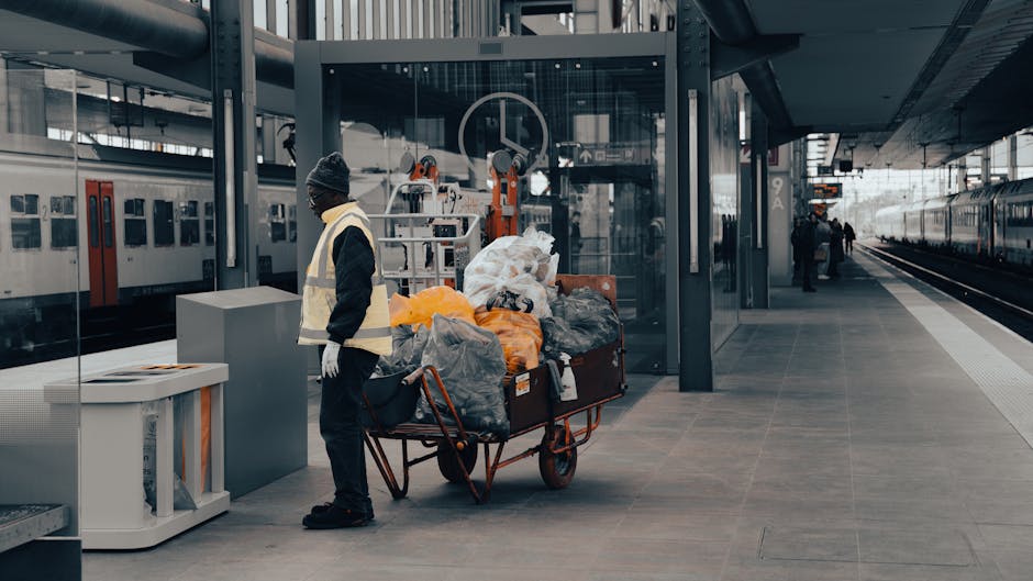 A collection of assorted rubbish materials arranged outdoors on a paved surface, including cardboard boxes, plastic containers, and paper waste, some of which are partially collapsed or torn. The item